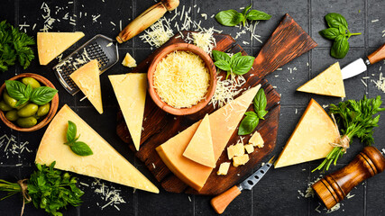 Cheese. Sliced ​​hard aged cheese and basil on a wooden cutting board.