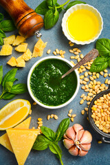 A bowl of homemade pesto sauce. Ingredients for making the sauce: basil, parmesan, nuts, lemon and...