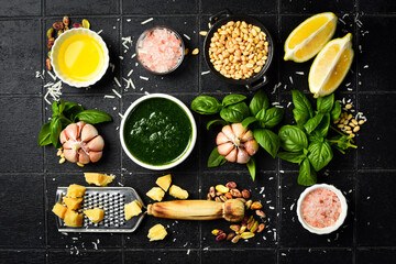 Pesto sauce and ingredients. On a black stone background. Creative photo. Top view.