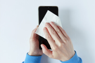 Caucasian woman wipes napkin smartphone screen with lint-free cloth holding it in her hands. White...
