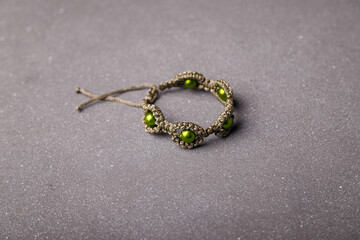 Green beaded bracelet from macrame yarn on grey background. Copy space