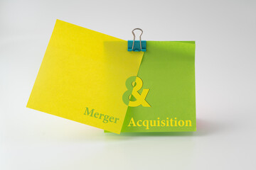 Two sticky notes stick together with text Merger and Acquisition (MA) on each part;  A concept...