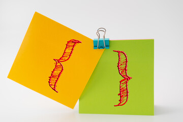 A  pair of curly braces on two sticky notes stuck together represent grouping or bringing things...