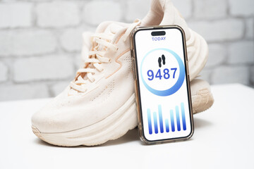Step-tracking app displayed next to white athletic shoes. Fitness and health concept. Mobile pedometer, active lifestyle, and daily activity monitoring
