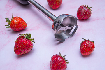 Blender next to fresh strawberries. Preparing a delicious and healthy smoothie. Concept of clean eating, fresh ingredients, and homemade nutrition