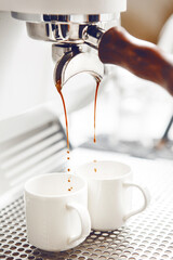 Close-up of Rich Espresso Pouring From Portafilter Into White Cups, Capturing Brewing Moment. 