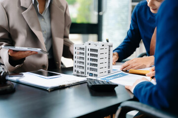 Business team consulting on real estate deal with building model, contract, and calculator. Ideal for property investment, legal agreement, and finance themes. © Nuttapong punna