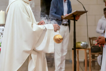 Obraz premium Prêtre catholique utilisant un encensoir pendant une cérémonie religieuse dans une église, lors d’un baptême ou d’une communion