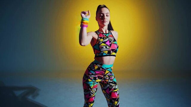 Professional zumba instructor posing confidently on a vibrant gradient background, showcasing colorful sportswear and sporting a neat ponytail, radiating energy and enthusiasm