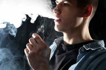 Man using electronic smoking device on black background