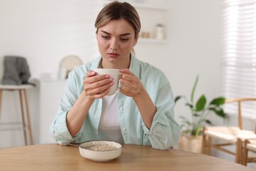 Depressed woman with appetite loss at table indoors
