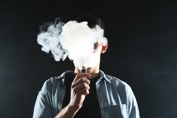 Man using electronic smoking device on black background