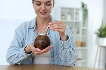 Woman with traditional yerba mate tea at table indoors, space for text