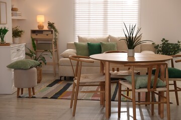 Stylish dining table with chairs and comfortable sofa in room. Interior design
