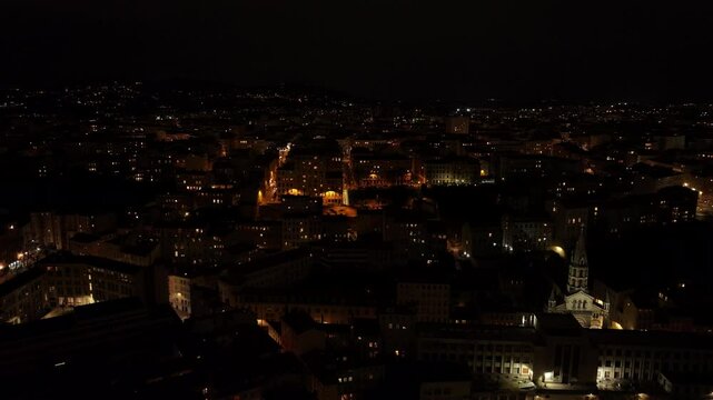 Dark aerial view of Lyon cityscape illuminated at night, featuring Bon Pasteur church, streets with traffic in this french tourist destination