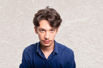 Young handsome student in blue shirt looking seriously at camera. Isolated on white background....
