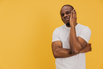 Young African American Man Suffering From Toothache on Yellow Background