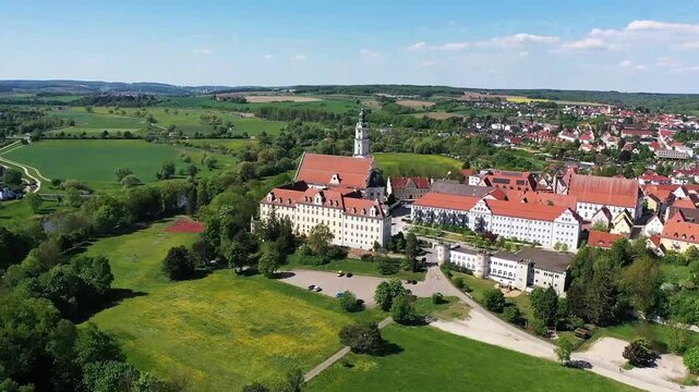 Luftaufnahme von Donauw&ouml;rth mit roten D&auml;chern, historischen Geb&auml;uden und einem markanten Turm, eingebettet in eine gr&uuml;ne Landschaft. Die Stadt bietet eine charmante Kulisse. 