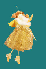Rag doll with thin legs in a golden dress princess outfit. Hanging Christmas decoration. Turquoise background.