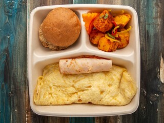 Cheese Omelette Meal with Potato Wedges and Bread Roll in Eco-Friendly Tray – Top View