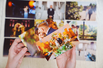 hands with photos and Printed wedding photos laid out on a wooden surface.