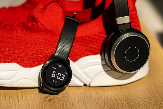 Running essentials for an active lifestyle – smart watch, wireless headphones, and red sports shoes ready to support your fitness journey and healthy daily routine - Powered by Adobe