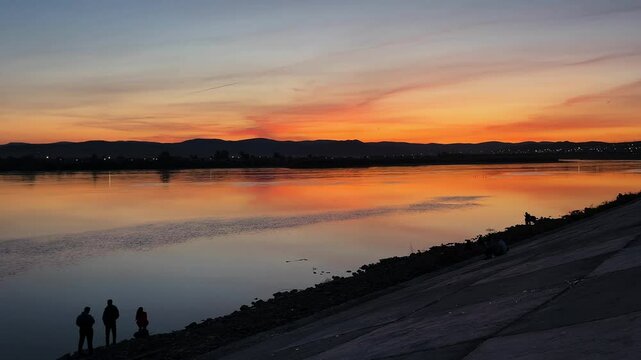 sunset over the river. people on the riverbank embankment