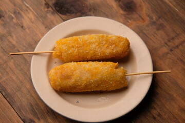 A corn dog is a hot dog on a stick that has been coated in a thick layer of cornmeal batter and deep fried