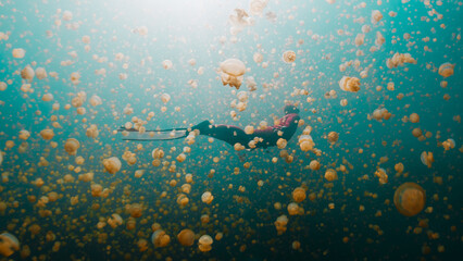 Freediver swims underwater in the lake full of jellyfish. West Papua, Misool, Indonesia