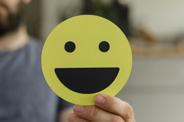 Stock photo of a person holding a happy smiley face. Perfect for positive emotions, happiness, and...