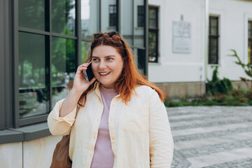 Lifestyle portrait of a stylish young 30s woman talking on cell phone, making call and standing on...