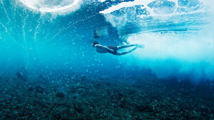 Man dives and swims underwater under the breaking wave