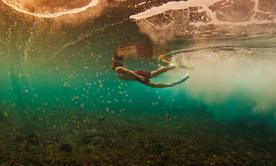 Man dives and swims underwater under the breaking wave