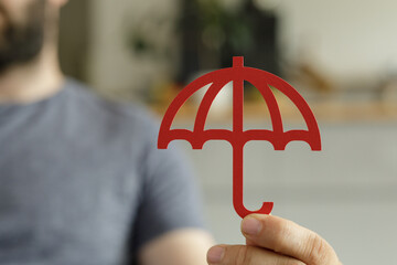 Stock photo of a person holding a red umbrella, symbolizing safety and security. Ideal for...