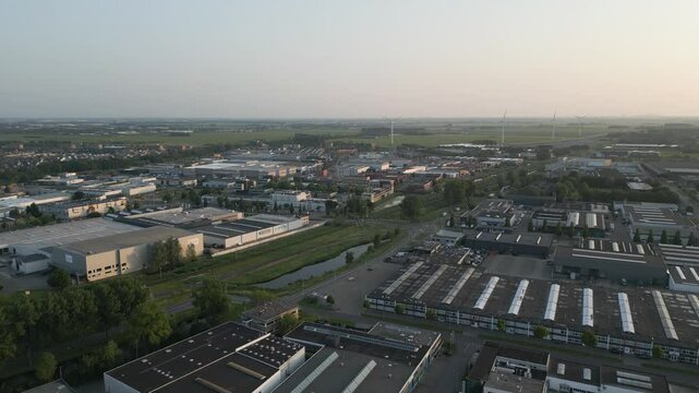 Aerial wide shot of a large-scale industrial area with warehouses and factories in Alphen aan den Rijn, during golden hour.