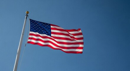 Obraz premium American Flag Waving High with Stars Stripes, Patriotism, and Blue Sky Backdrop.