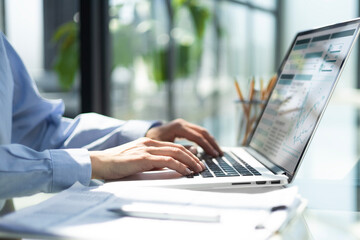 womans hands analyzing financial data on laptop screen in hybrid office setting for digital entrepreneurship