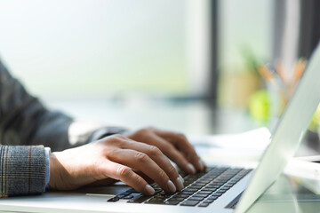 Close up of business woman hands typing on laptop computer, searching and surfing the internet on office desk