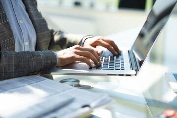 Close up of business woman hands typing on laptop computer, searching and surfing the internet on office desk