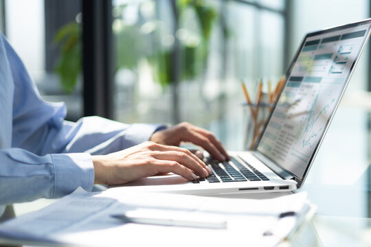 womans hands analyzing financial data on laptop screen in hybrid office setting for digital entrepreneurship