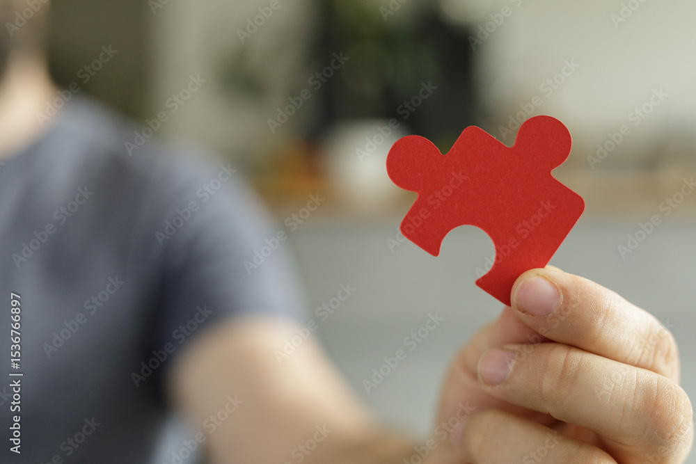Poster A man holds a single red puzzle piece, symbolizing solutions, teamwork, and problem-solving.