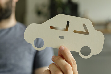 Image of a person holding a paper car cutout, ideal for auto insurance, car loans, or vehicle purchase concepts.