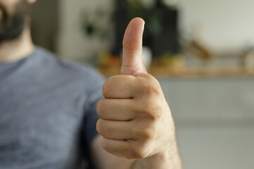 Close-up of a man's hand showing a thumbs up.  Positive, approval, success.