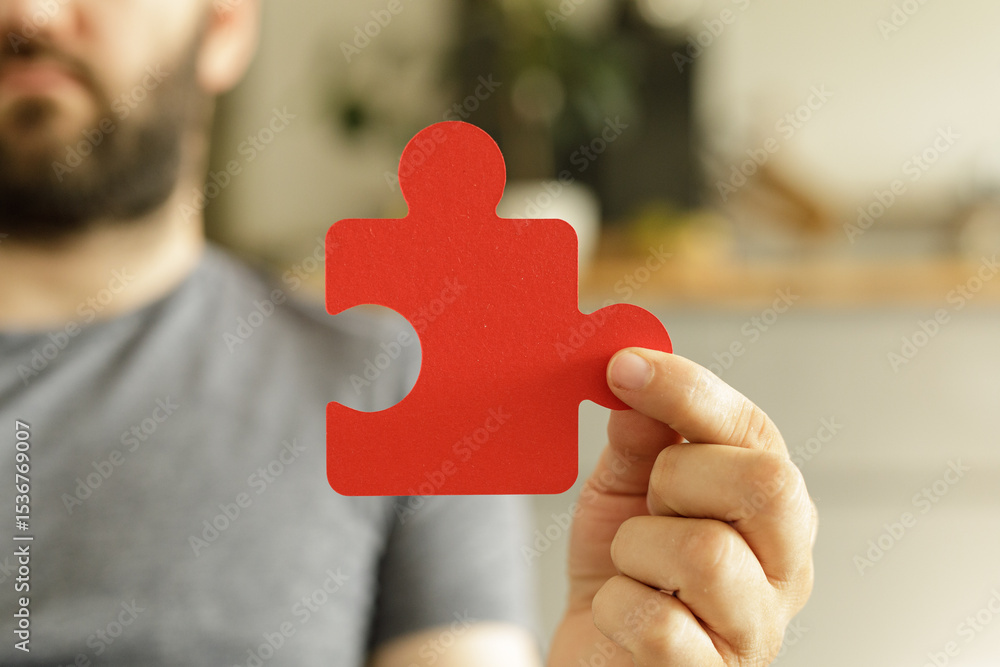 Poster a man holds a single red puzzle piece, symbolizing solutions, teamwork, and problem-solving.