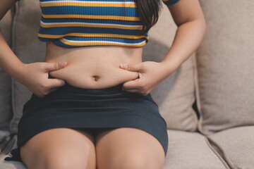 Cropped shot of woman touching and squeezing her fat belly.