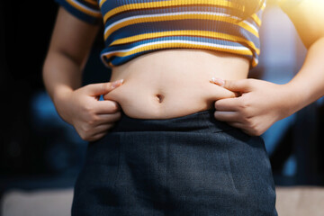 Cropped shot of woman touching and squeezing her fat belly.