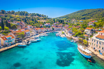 Aerial view of the tranquil bay in Stomorska on Solta Island, Croatia, featuring crystal-clear turquoise Adriatic waters, traditional seaside houses, and lush greenery in a peaceful setting
