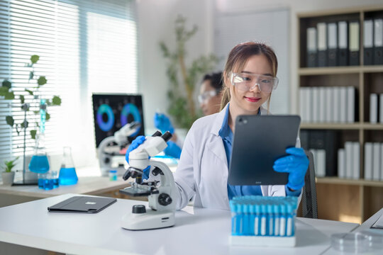 A woman in a lab coat is holding a tablet and looking at it