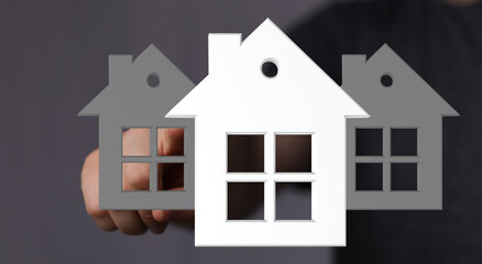 Image of a hand choosing a house, representing real estate, property selection, and home buying.