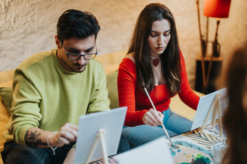 Two friends are seated, focusing on creating artwork on canvases in a cozy setting.